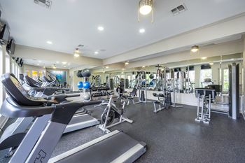 a gym with treadmills and other exercise equipment in a building with windows