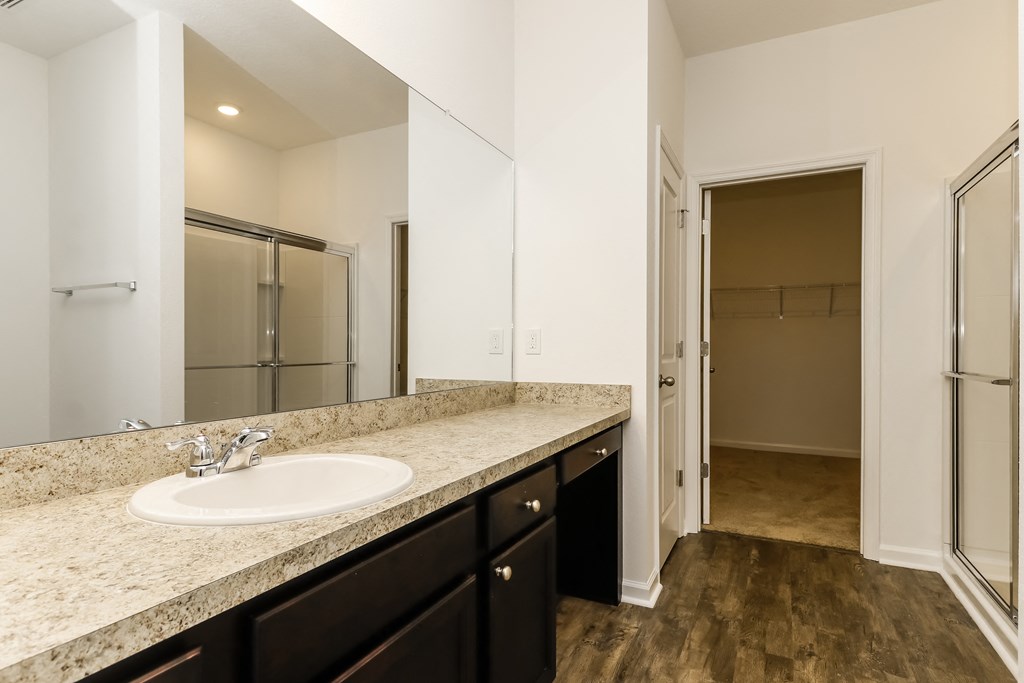 A bathroom with a sink, mirror, and wooden floor.
