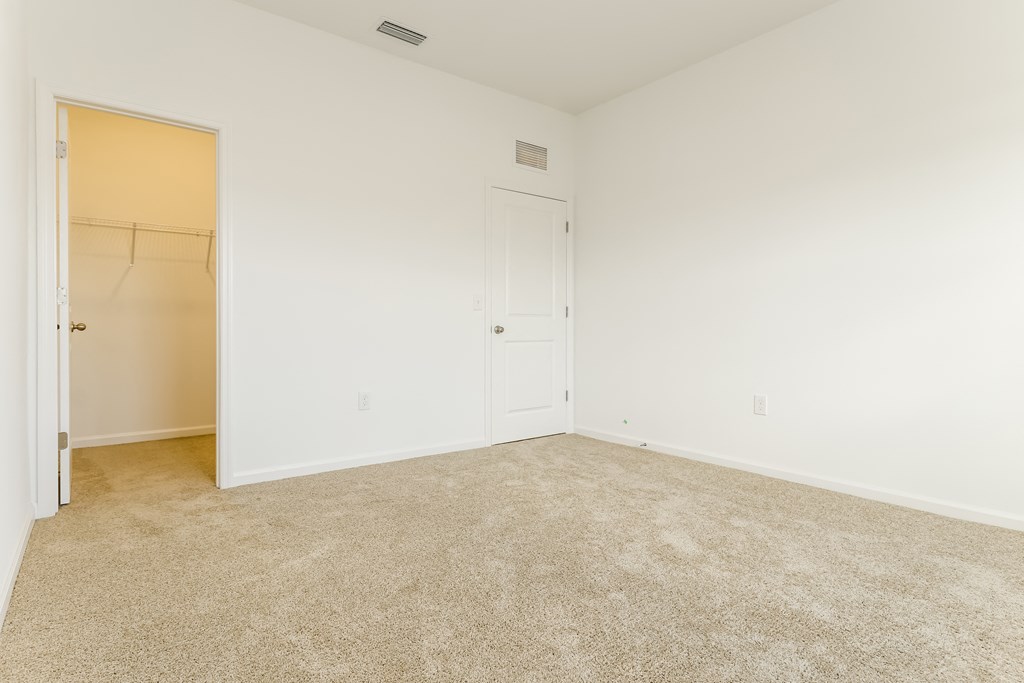 A room with a carpeted floor and a door on the left.