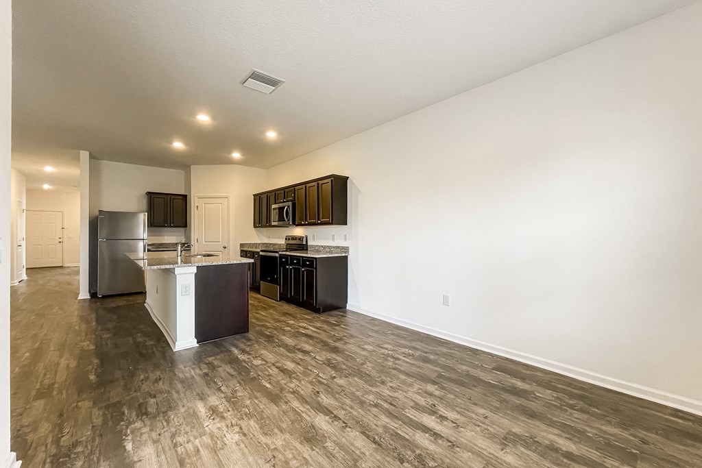 A kitchen with a refrigerator, sink, and cabinets.