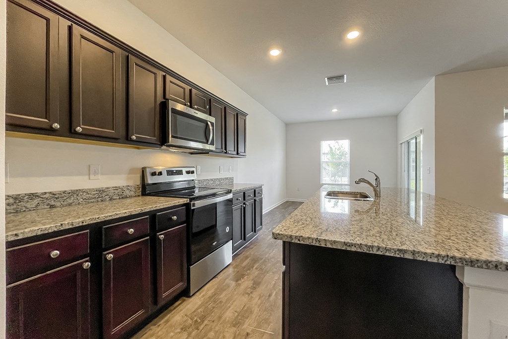 A kitchen with dark brown cabinets and a granite countertop.
