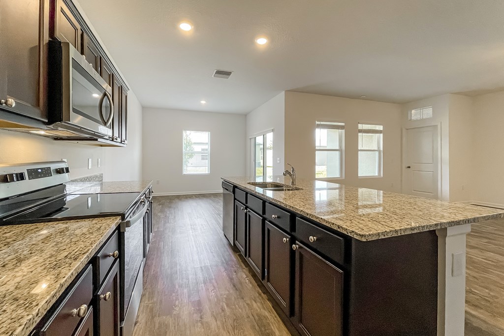 A kitchen with dark wood cabinets and granite countertops.