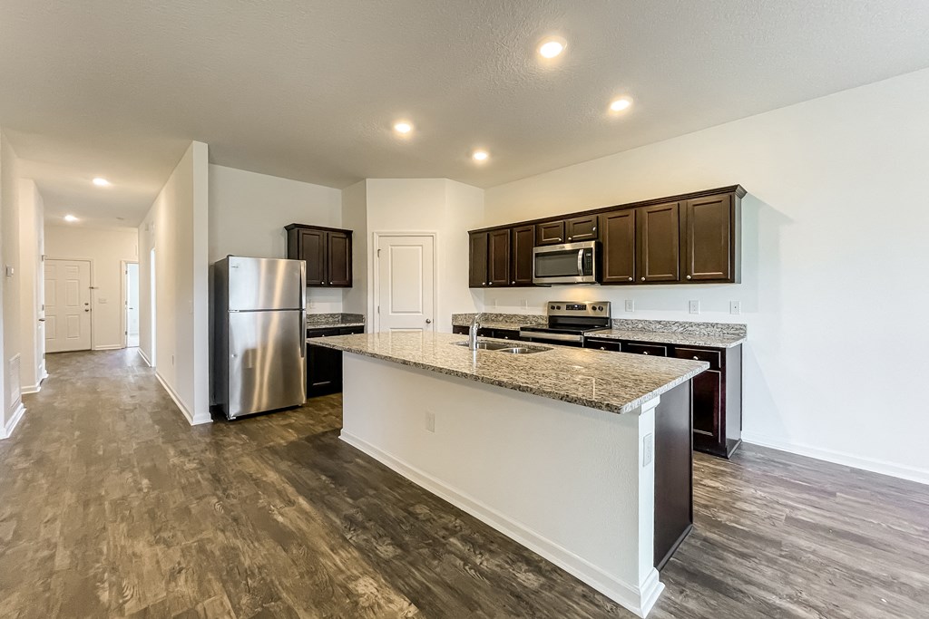 A kitchen with a white island and dark wood cabinets.
