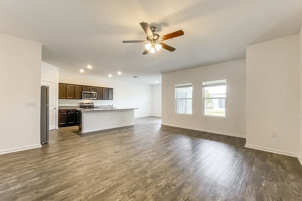 A spacious living room with a ceiling fan and hardwood flooring.