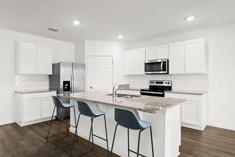 A kitchen with white cabinets and a granite countertop.