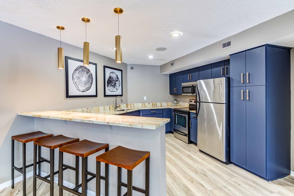 a kitchen with blue cabinets and a bar with stools
