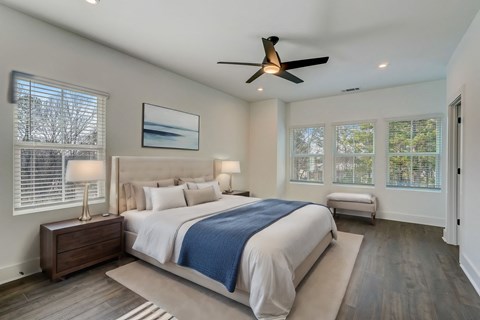 Henley Avondale Townhomes near Scottdale, GA master bedroom with a large bed, ceiling fan, and hardwood floors.