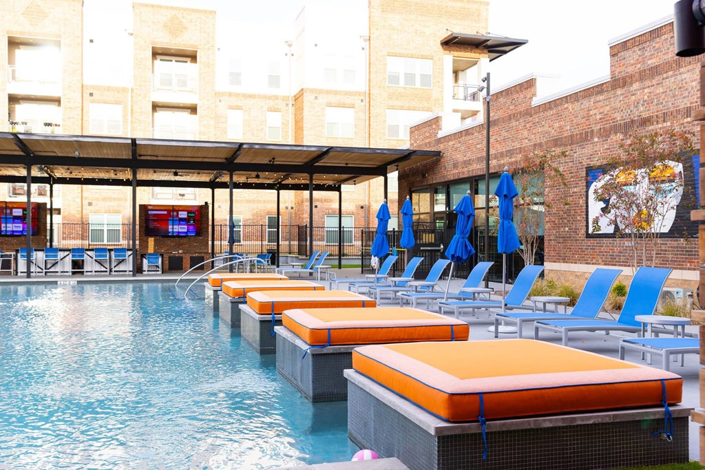 a resort style pool with blue chairs and orange cushions