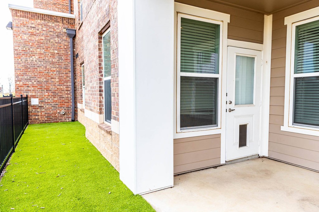 the front porch of a brick house with grass