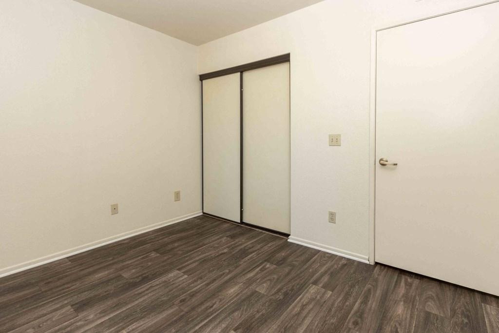 High Desert Villas apartments in Victorville California photo of a bedroom with white walls and wood flooring and a closet