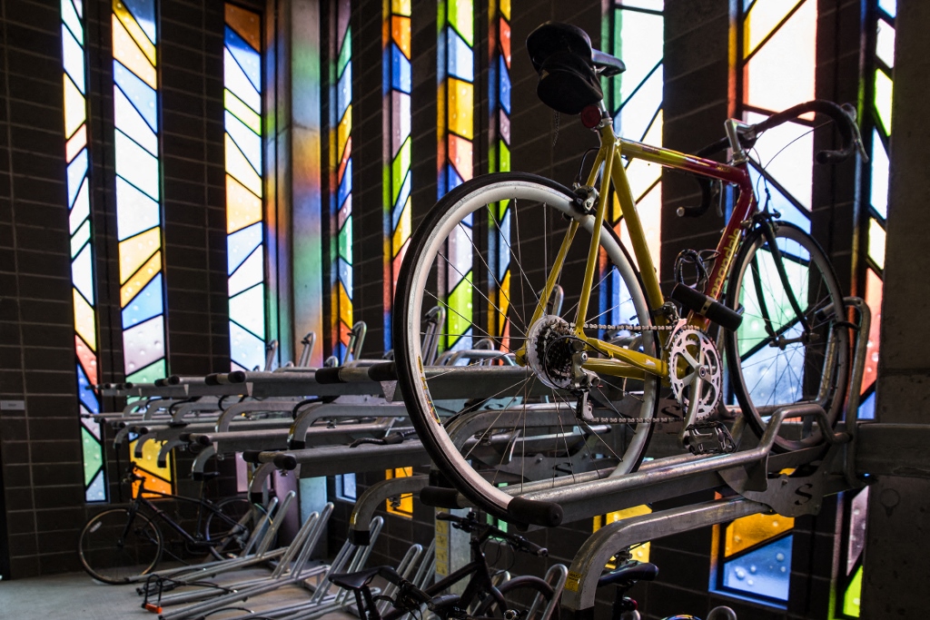 NW Portland, OR Apartments - The Muse - Bike-Storage-Room With Bike Racks, And Vibrant Stained Glass Windows