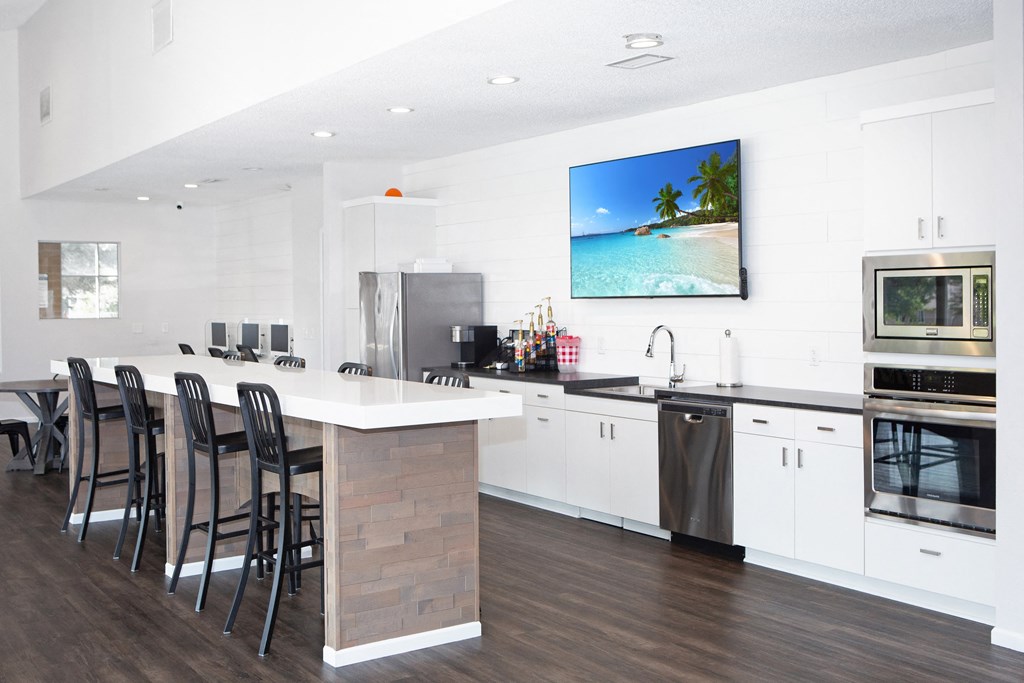 Hinton Height_Cottage Grove_MN_a white kitchen with a bar and chairs and a tv on the wall