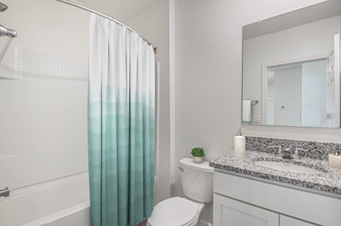 A white bathroom with a toilet, sink, and shower curtain.