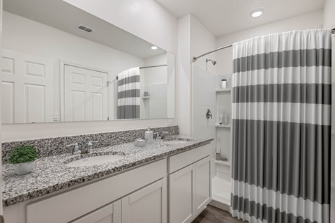 A bathroom with a striped shower curtain and a marble countertop.