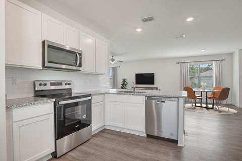 A modern kitchen with white cabinets and stainless steel appliances.