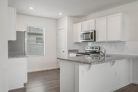 A kitchen with white cabinets and a granite countertop.