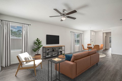 A living room with a brown couch, a television, and a ceiling fan.