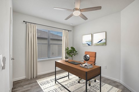 A room with a brown desk and a ceiling fan.