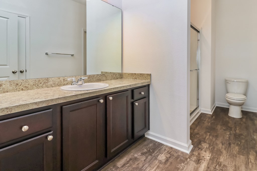 A bathroom with a marble countertop and dark wood cabinets.