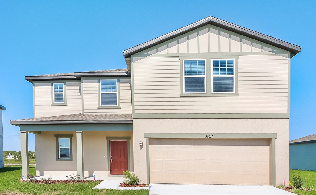 A two-story house with a red door and garage door.