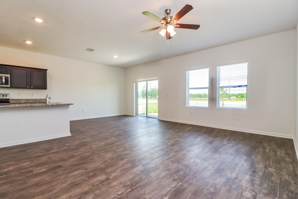 A spacious room with a ceiling fan and wooden flooring.