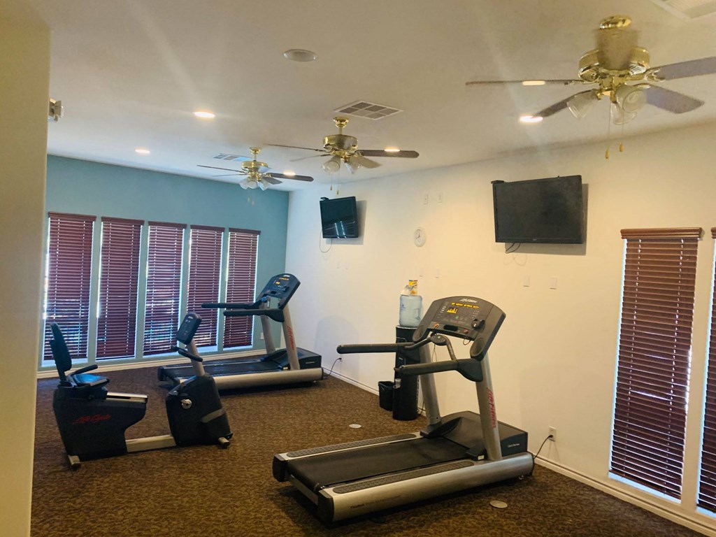 a workout room with treadmills and a tv