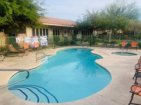 a swimming pool with chairs around it in front of a house