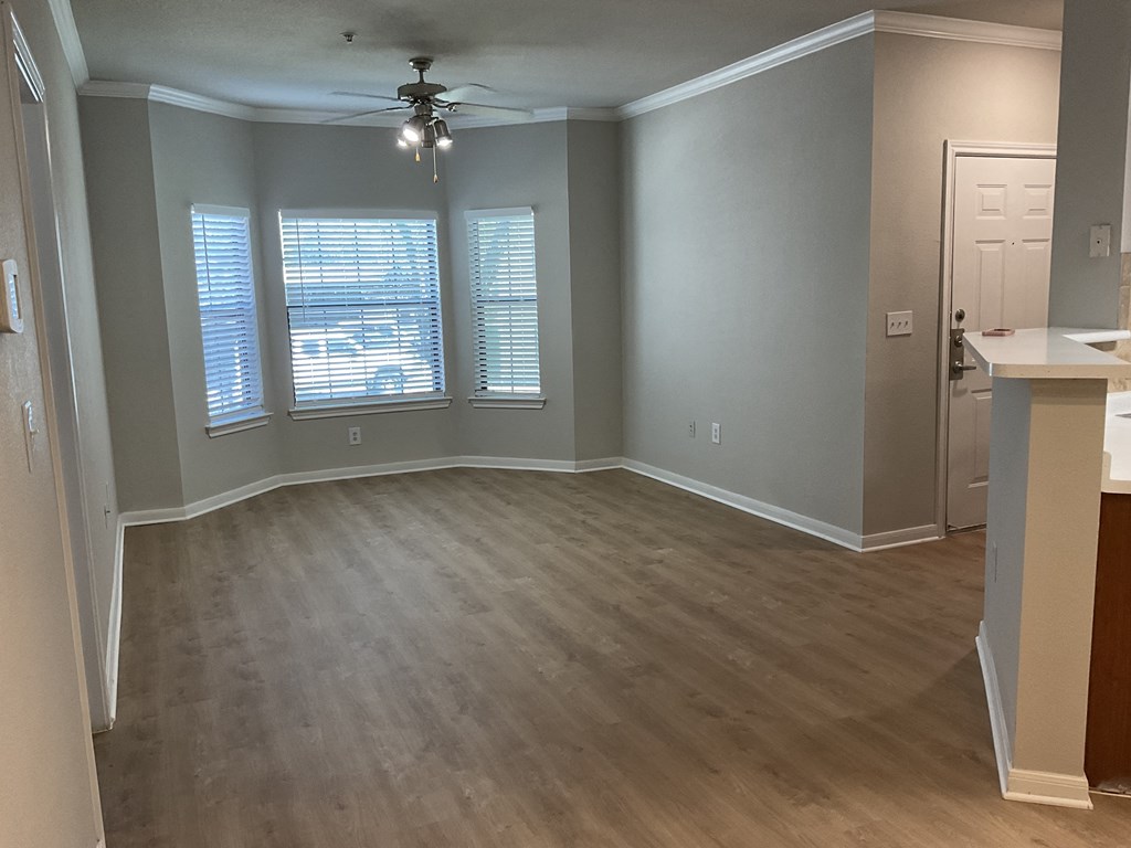 an empty living room with wood floors and a ceiling fan