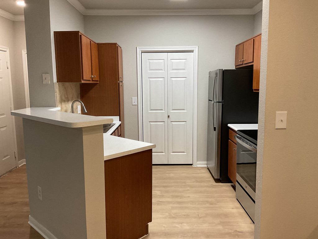 an empty kitchen with wooden cabinets and a black refrigerator