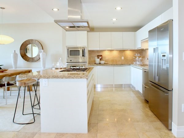 A modern kitchen with a white island and stainless steel appliances.