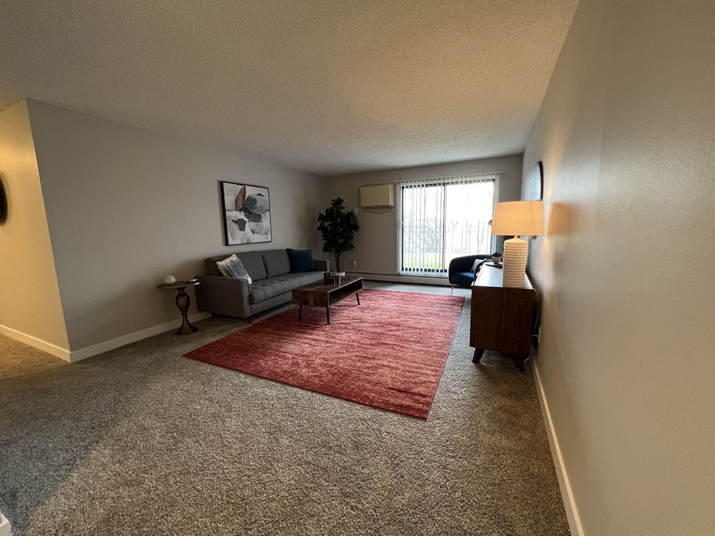 an empty living room with a red rug and a couch
