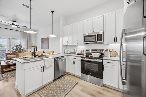 A modern kitchen with white cabinets and stainless steel appliances.