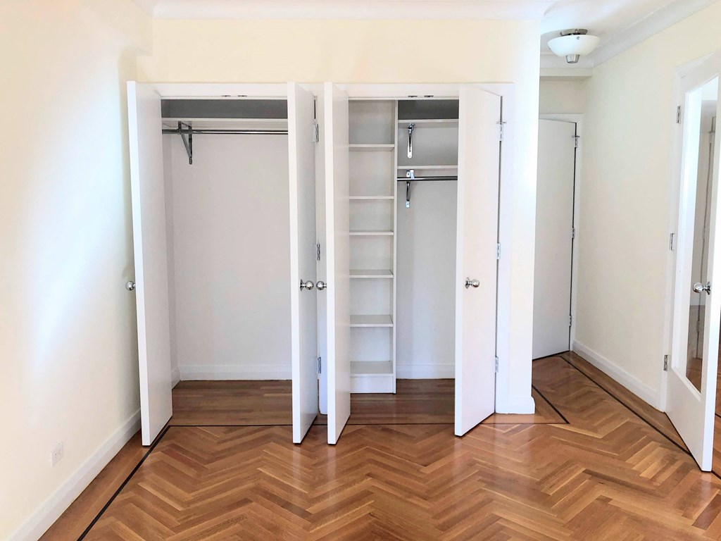 a bedroom with a medium hardwood floor and a closet with two doors