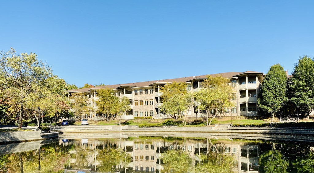 an apartment complex with a lake in front of it