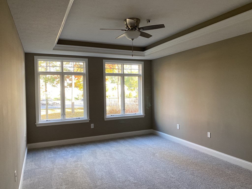 an empty room with a ceiling fan and three windows