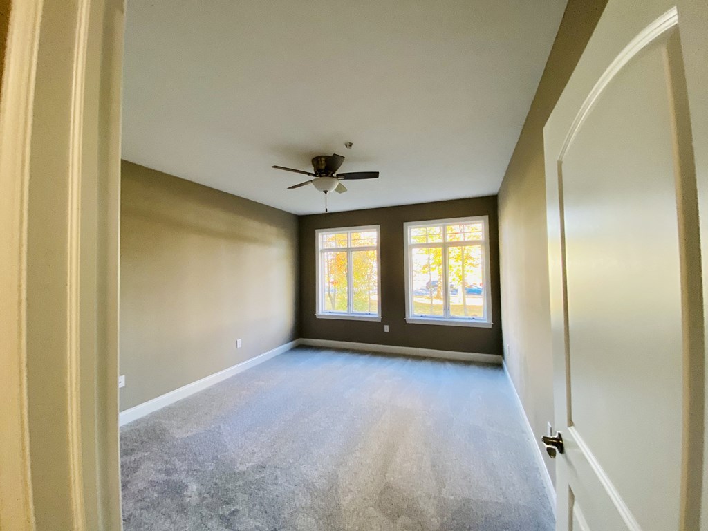 an empty room with a ceiling fan and three windows