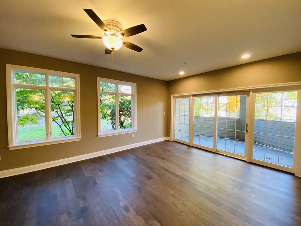 an empty living room with a ceiling fan
