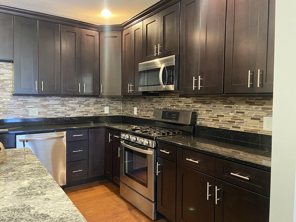a kitchen with dark cabinets and granite countertops