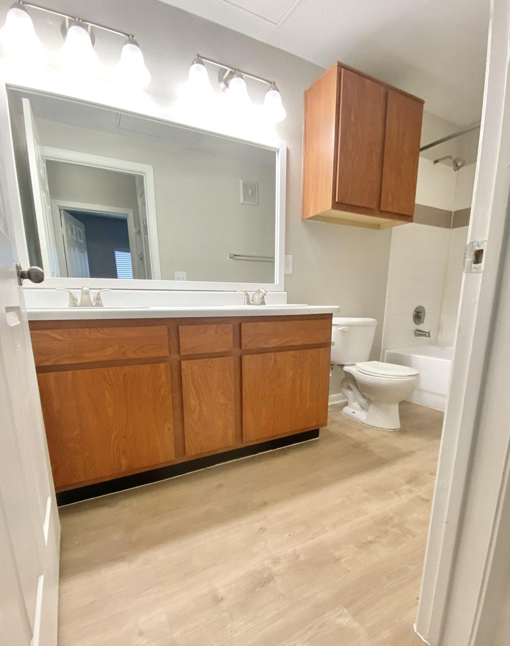 Bathroom with bright lights and wood cabinets and double vanity