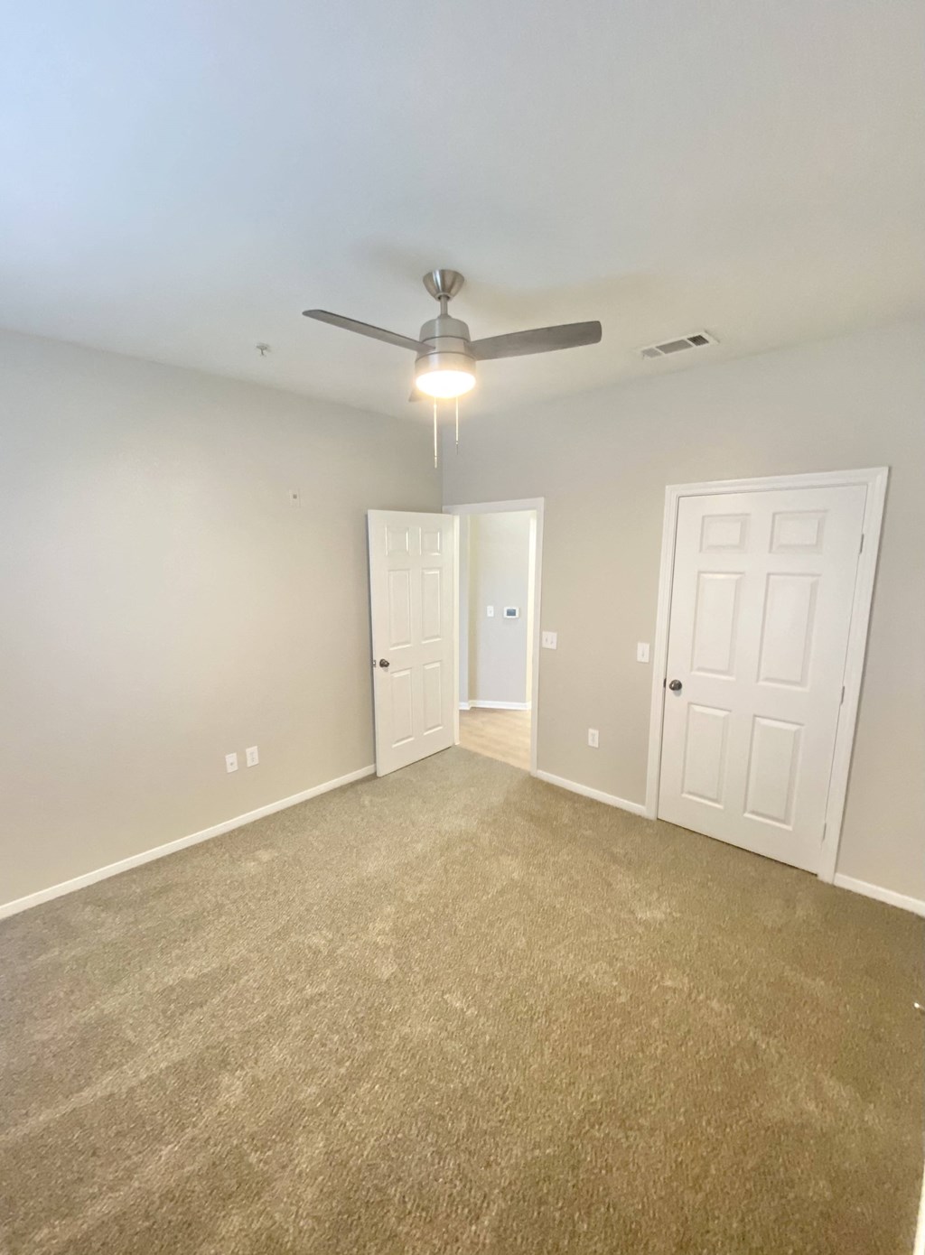 A  bedroom with carpet floor and ceiling fan and white doors