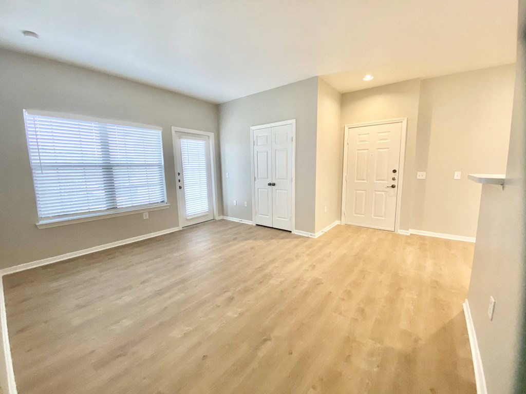 A living room with wooden floors and doors and windows