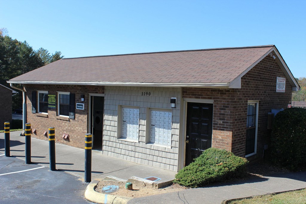 the front of a small brick building with a parking lot