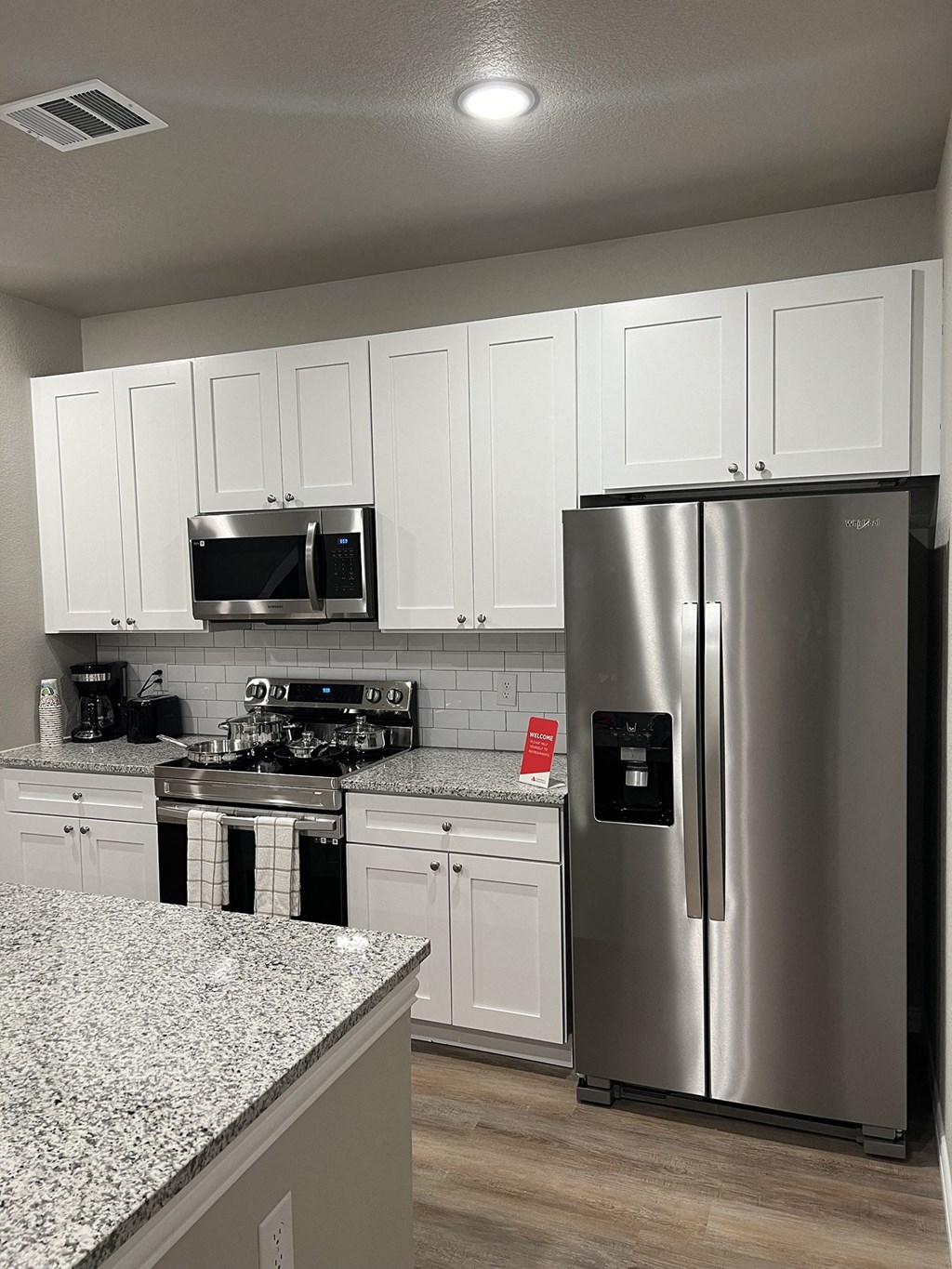 a kitchen with white cabinets and a stainless steel refrigerator