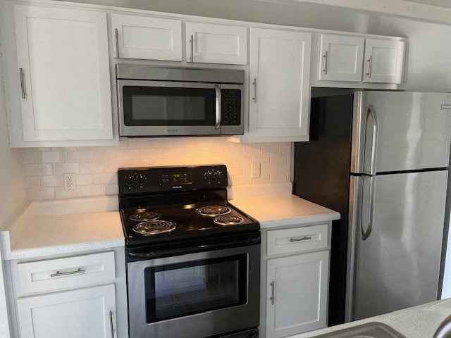 a kitchen with a stove refrigerator and microwave