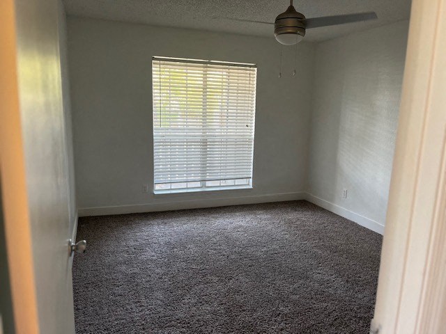 an empty room with a window and a ceiling fan