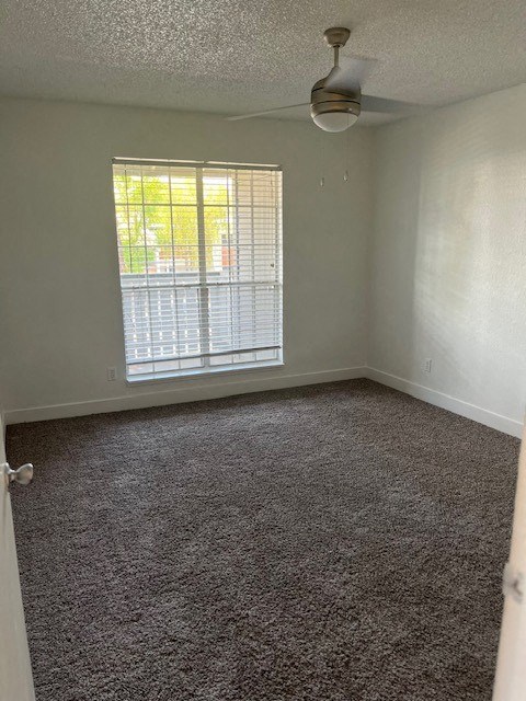 an empty room with a window and a ceiling fan