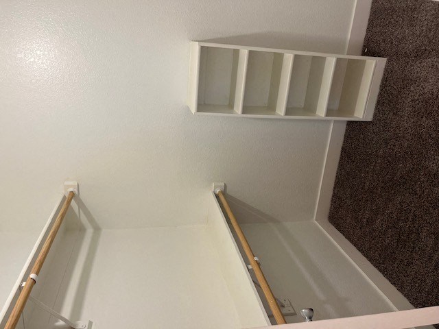 a room with a staircase and a shelf on the wall