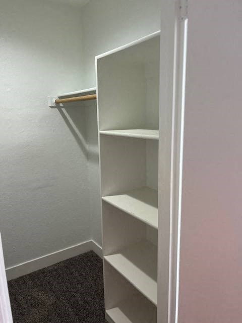 a white closet with white shelves and a towel rack