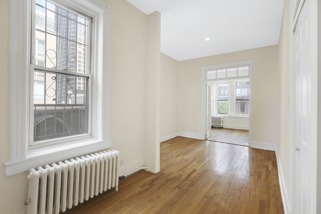 a living room with wood floors and a large window and a radiator
