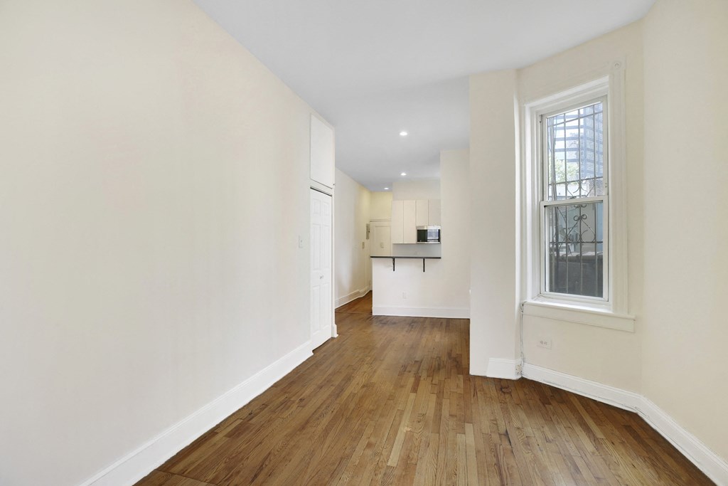 a living room and kitchen with white walls and wood floors